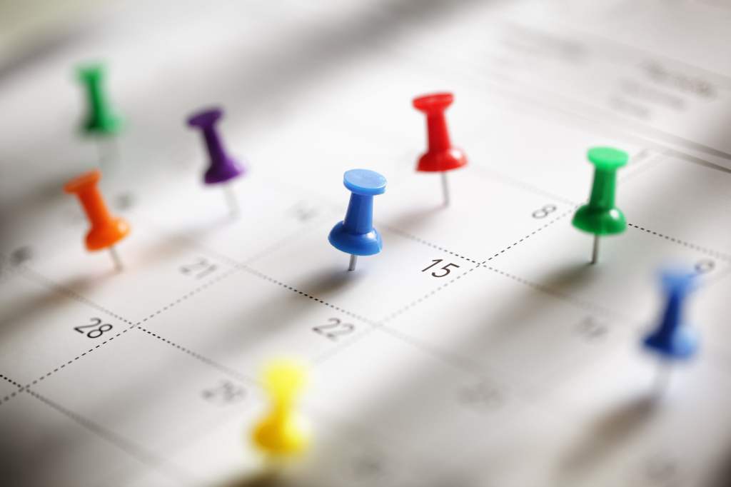 a close-up of a calendar with colored push pins