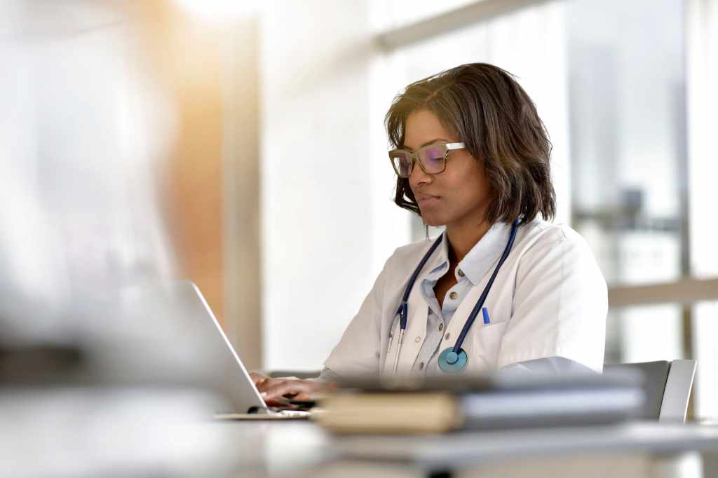 A female doctor with short hair typing on her laptop